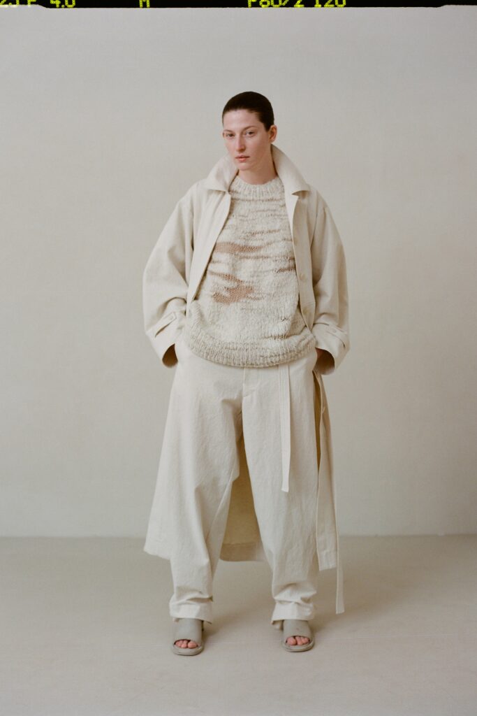 A relaxed beige coat layered over a long-sleeve sweater, creating a stylish ensemble.