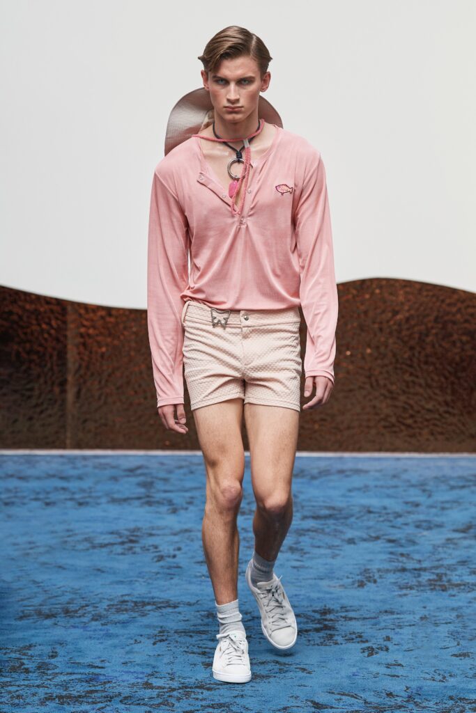 A fitted pink long-sleeve shirt with a collar paired with white striped shorts.
