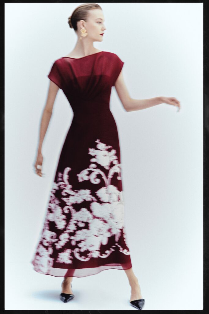 A fitted burgundy silk sleeveless dress with a high neckline and flared silhouette.