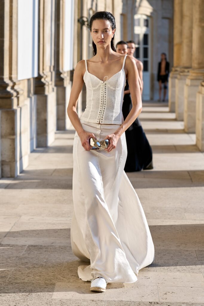 A fitted white silk dress with a sleeveless design and V-neckline, featuring a flowing silhouette.