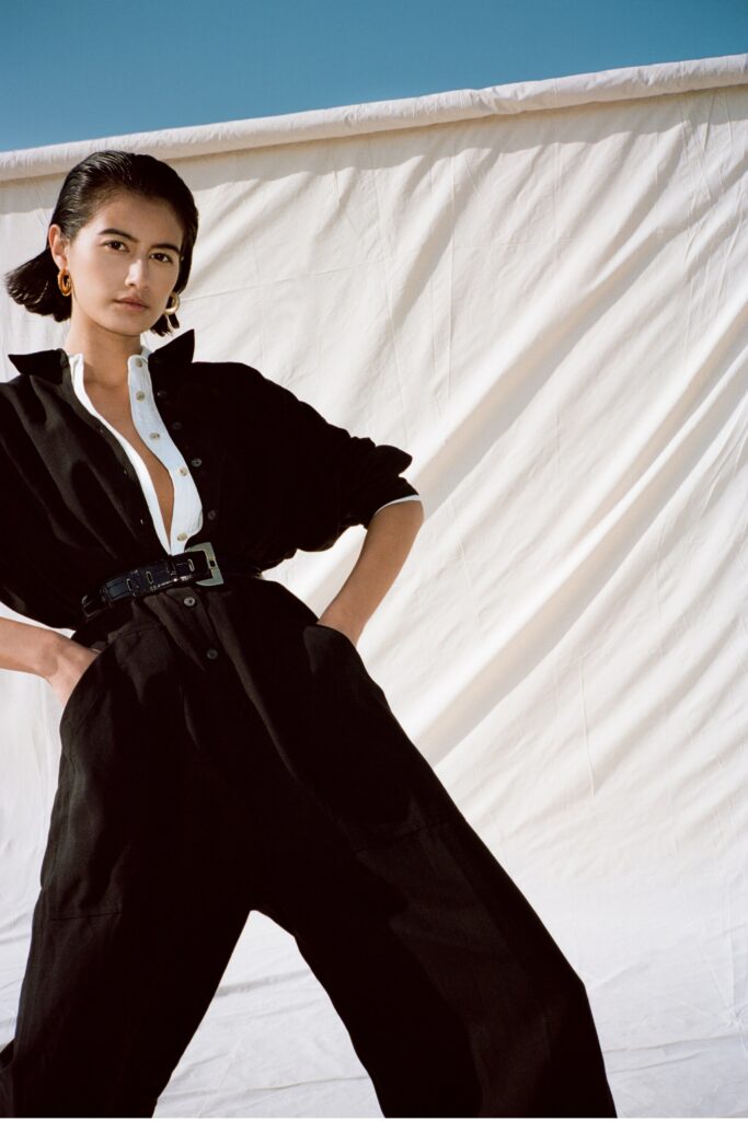 A relaxed black cotton jumpsuit with long sleeves and a collared neckline, featuring a buttoned front.
