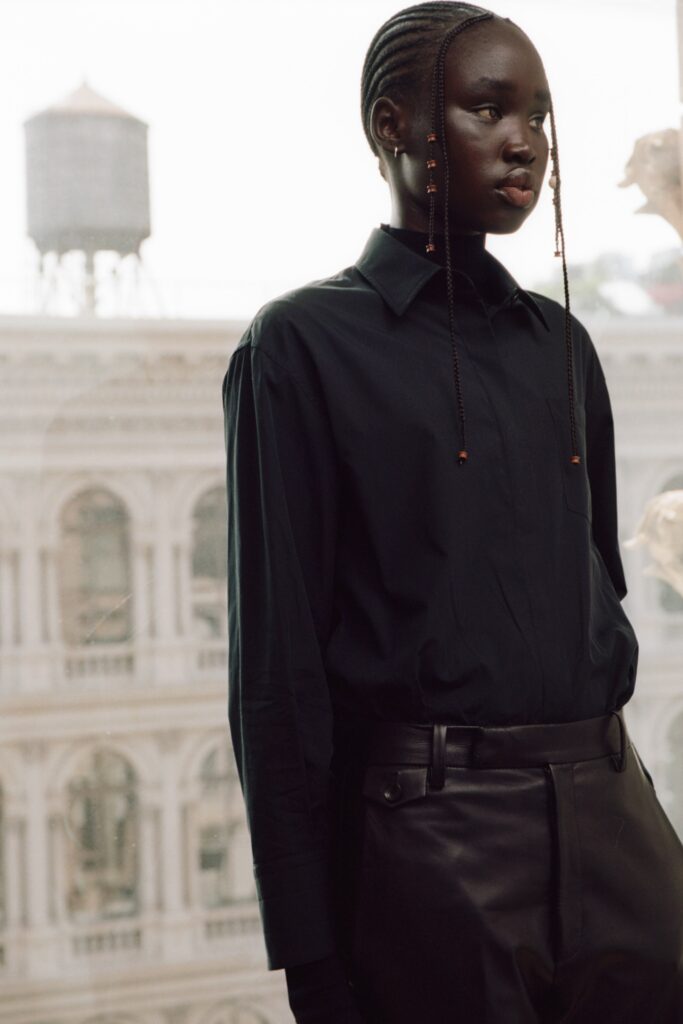 A fitted black cotton shirt with long sleeves and a collared neck paired with fitted leather pants.