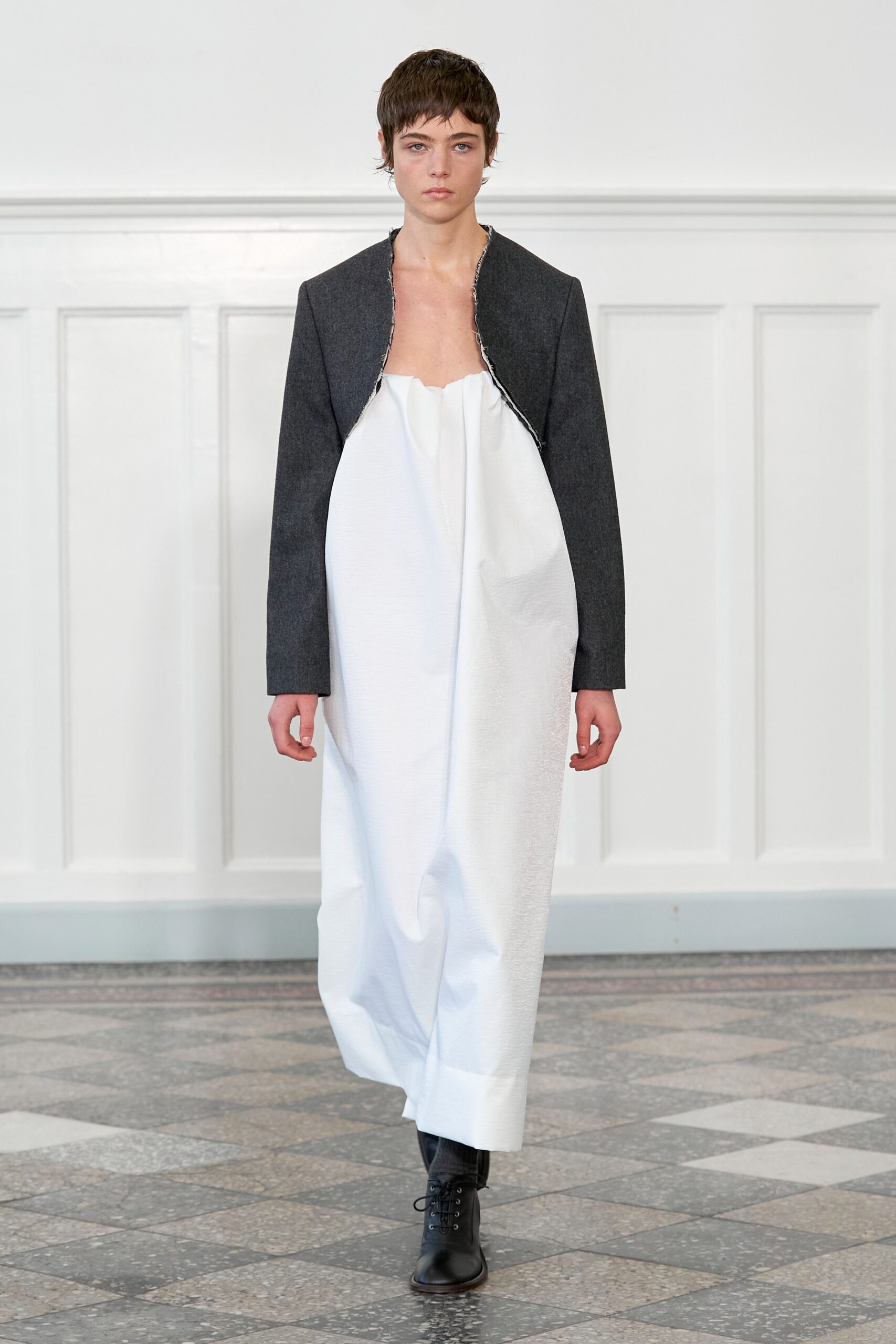 A relaxed fit black jacket over a sleeveless white dress with an asymmetric design.
