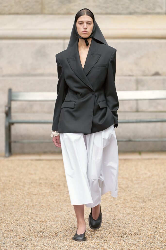 A relaxed black blazer with long sleeves paired with wide-leg white pants.