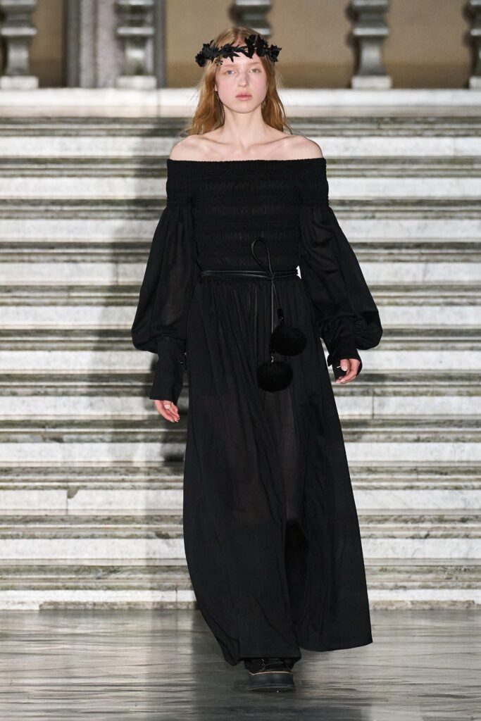 A relaxed black cotton maxi dress with long sleeves and an off-shoulder design.