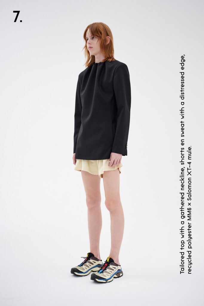A fitted black long-sleeve collared top paired with beige shorts featuring a distressed edge.