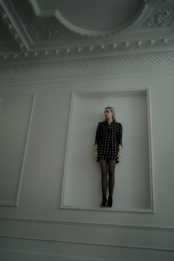 A fitted black dress with a checked pattern, long sleeves, and a collared neckline.