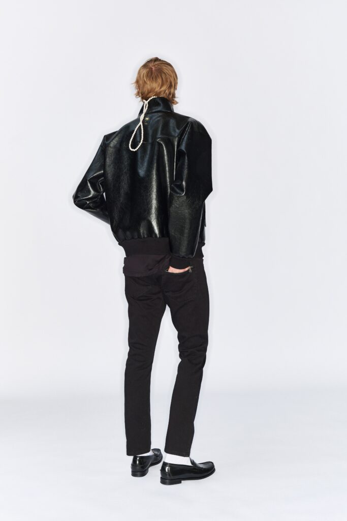 A fitted black leather jacket with long sleeves paired with black fitted pants.