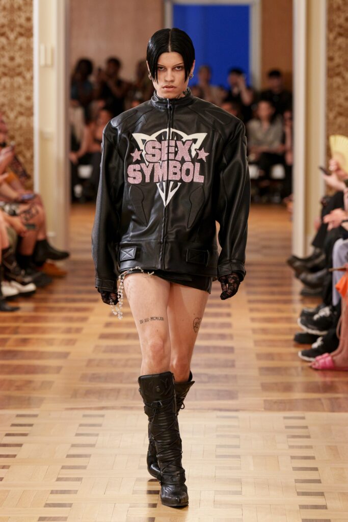 An oversized black leather jacket paired with a fitted black skirt, creating a bold fashion statement.