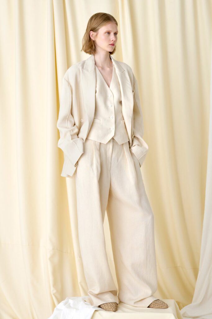 A relaxed beige linen suit featuring long sleeves and wide-leg trousers.