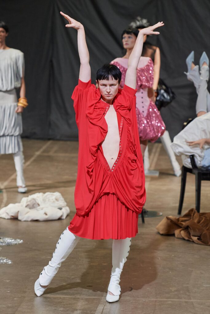 An oversized red silk sleeveless dress with a deep V-neckline and draped design.
