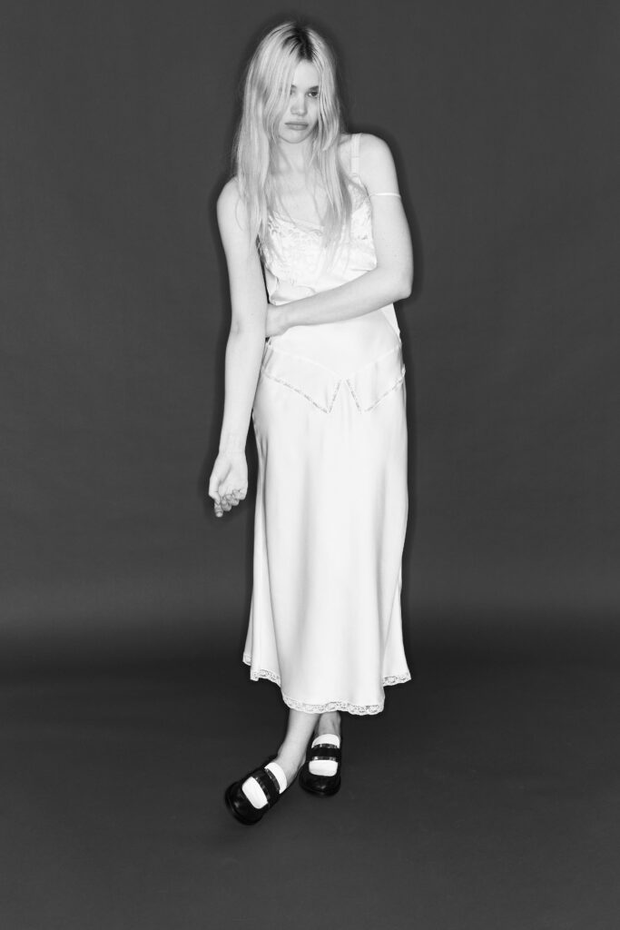 A fitted white silk sleeveless dress with a V-neckline and straight-leg silhouette.