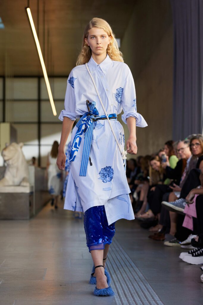 A blue and white buttoned cotton shirt-dress with long sleeves and floral accents.