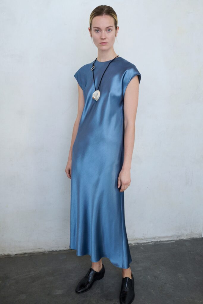 A relaxed blue silk sleeveless dress with a high neckline and straight-leg silhouette.