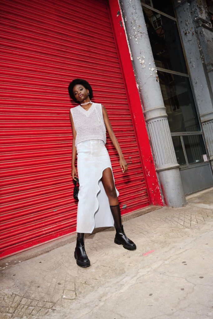 A fitted white sleeveless top paired with a layered skirt featuring a slit detail.