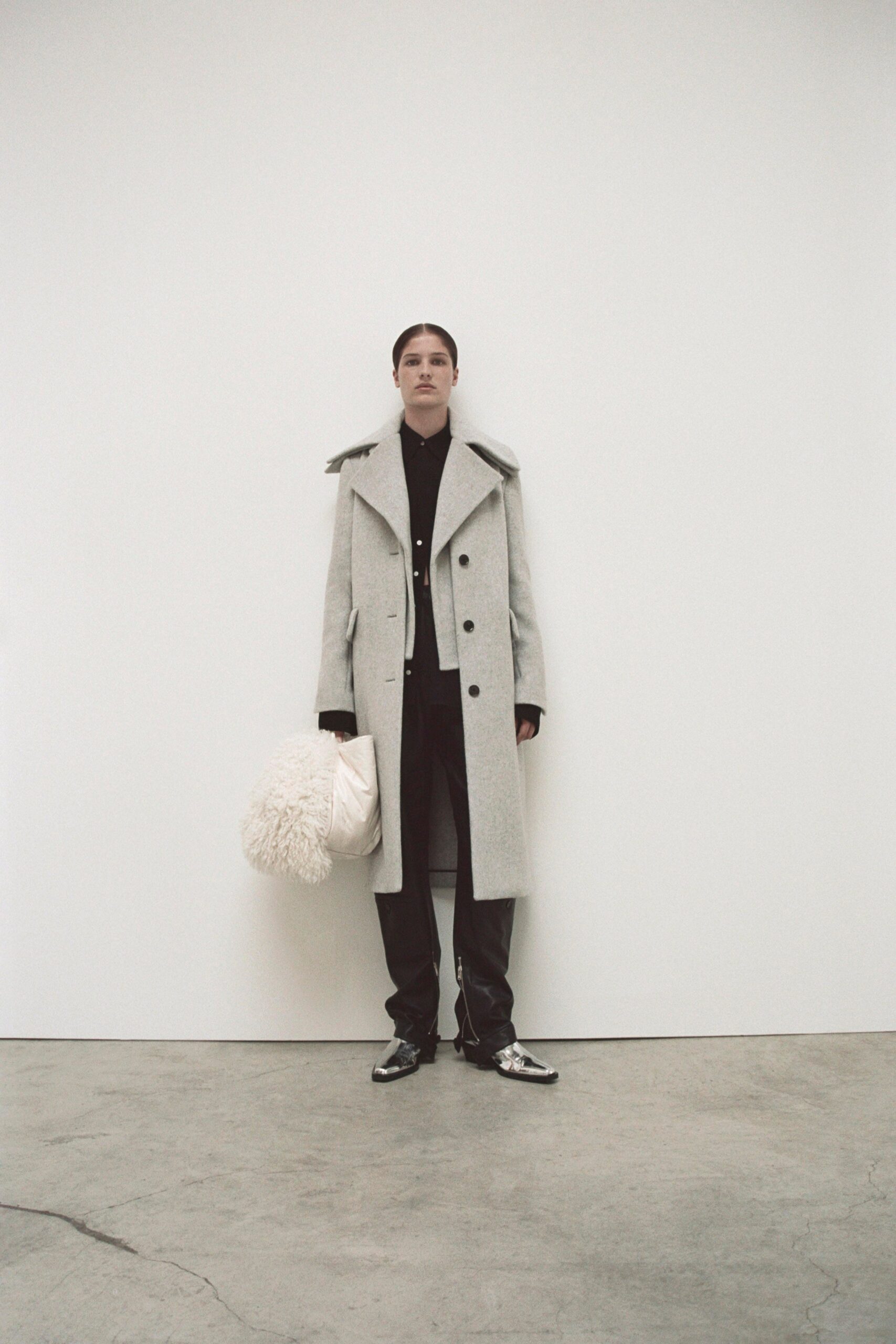 A relaxed gray wool coat paired with black leather pants featuring a collared design.