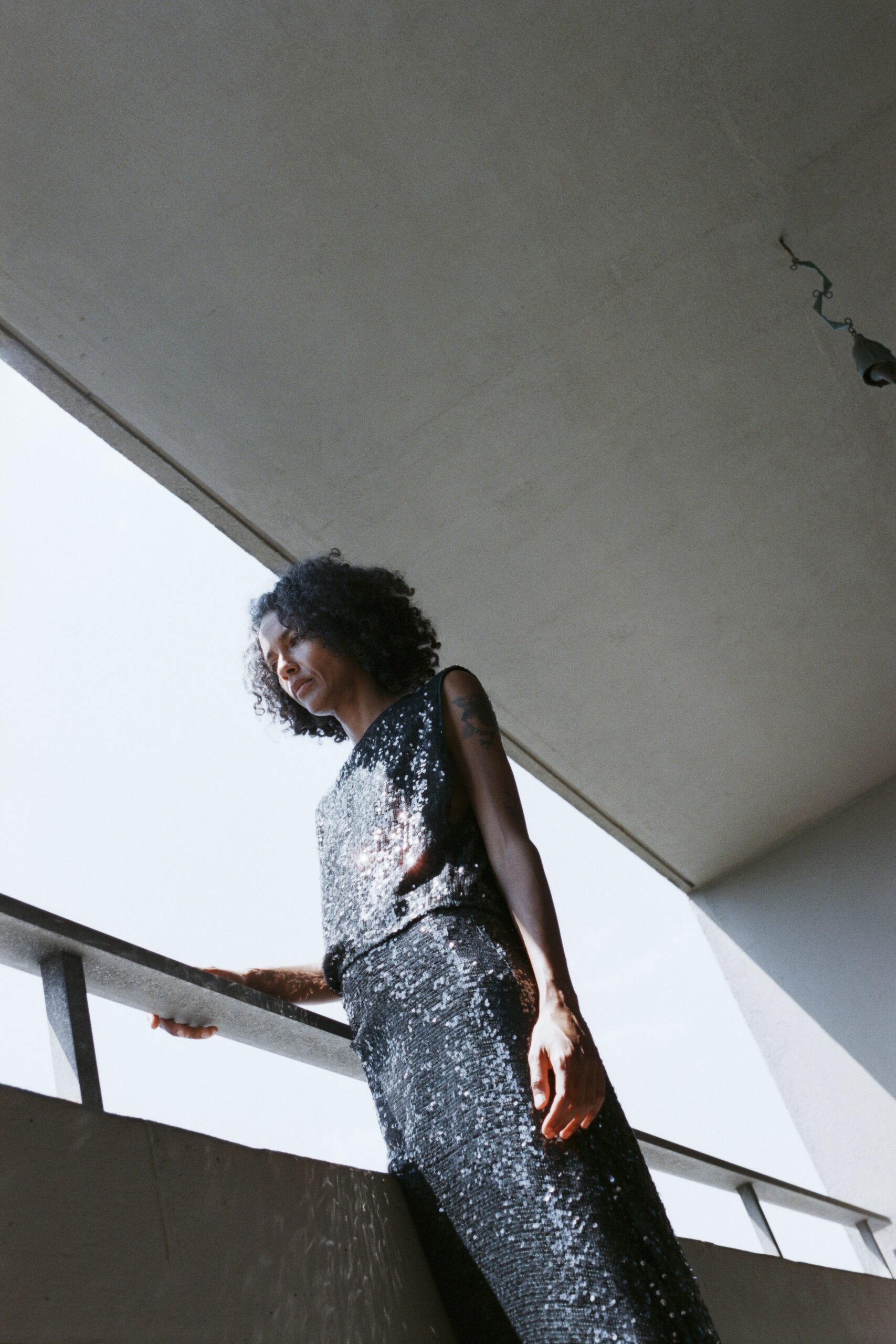 A fitted black sleeveless dress made of sequins with a high-neck design.