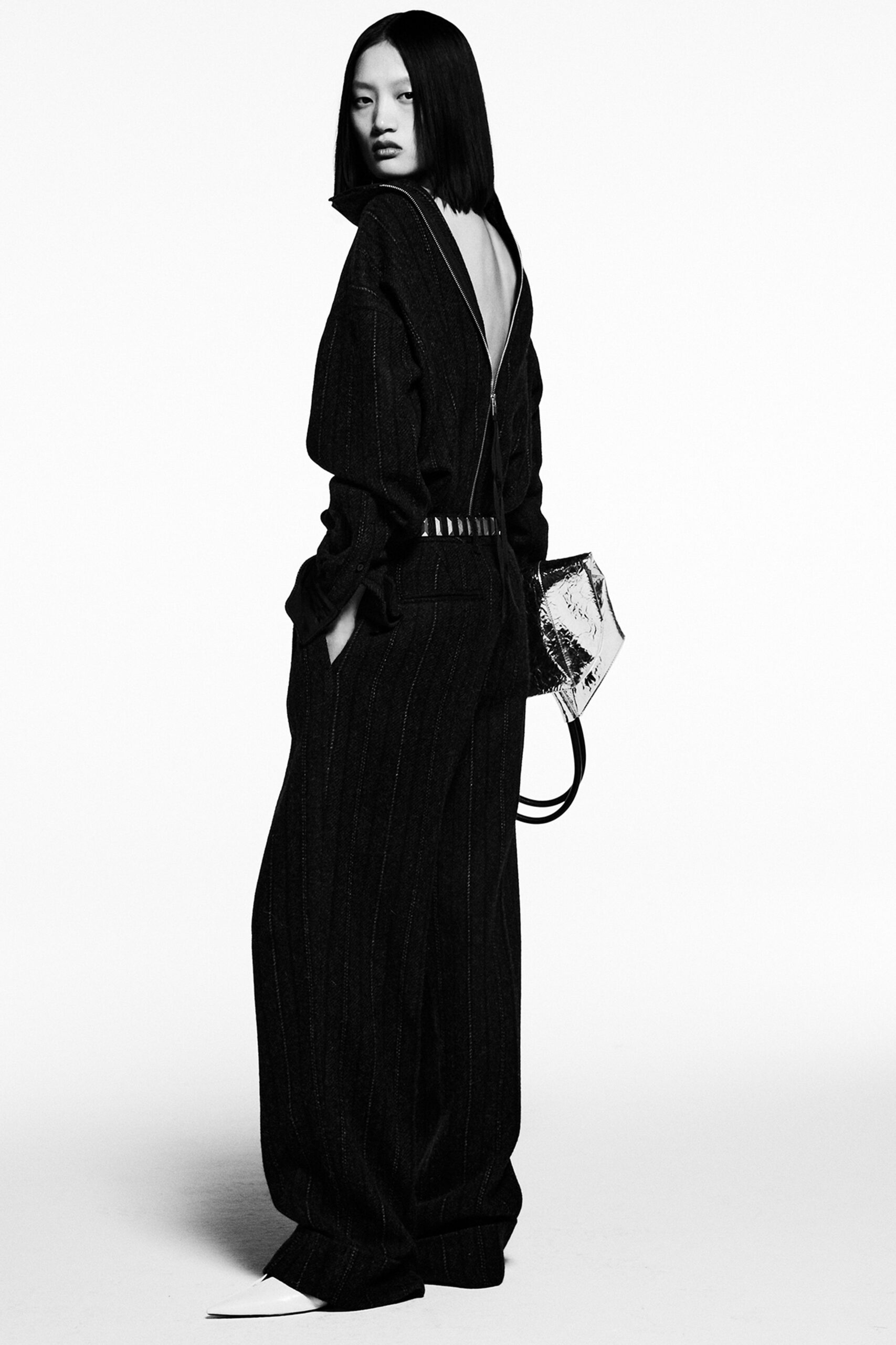 A relaxed black denim jumpsuit with long sleeves and a backless design featuring striped details.