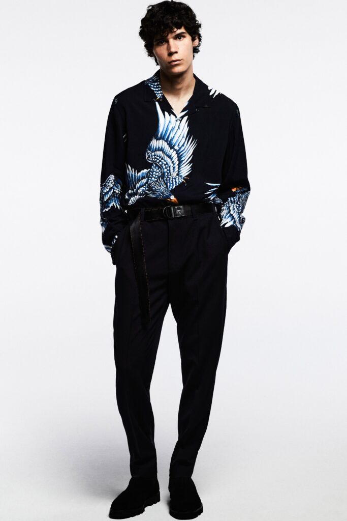 A relaxed black shirt with a blue printed design paired with black pants.