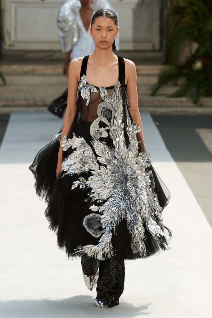 A relaxed black sleeveless dress with a V-neckline, layered design, and intricate silver embroidery.