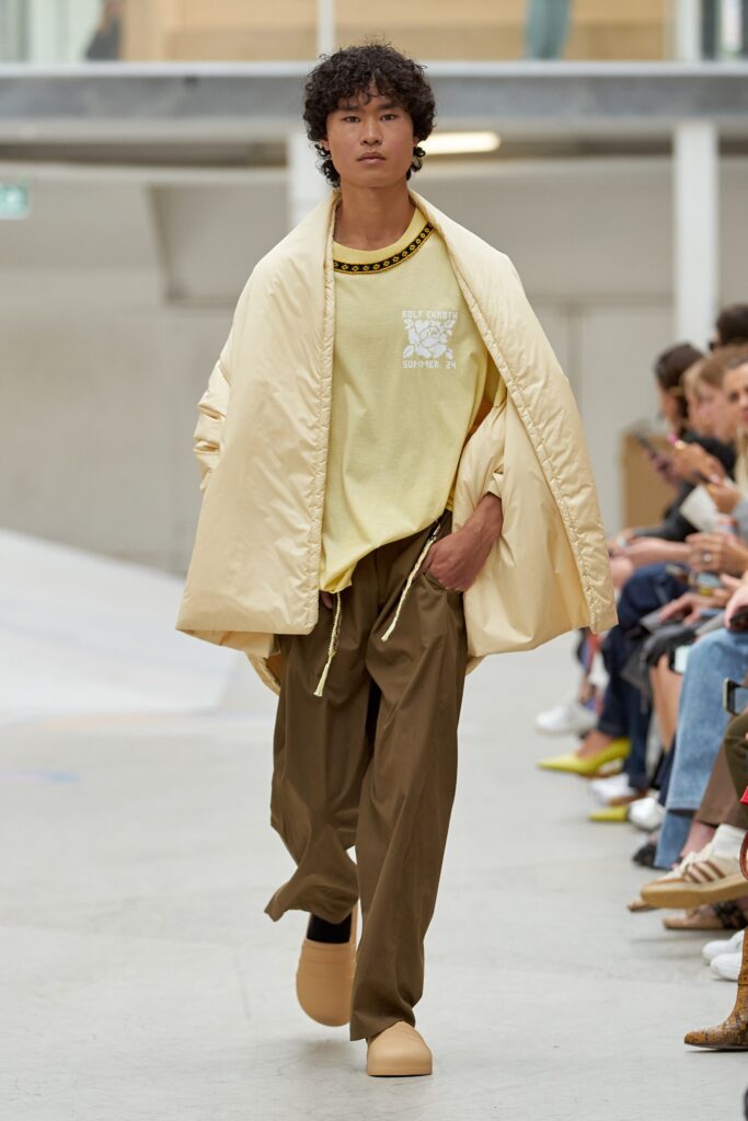 A relaxed beige jacket with long sleeves and a collared design paired with brown pants.