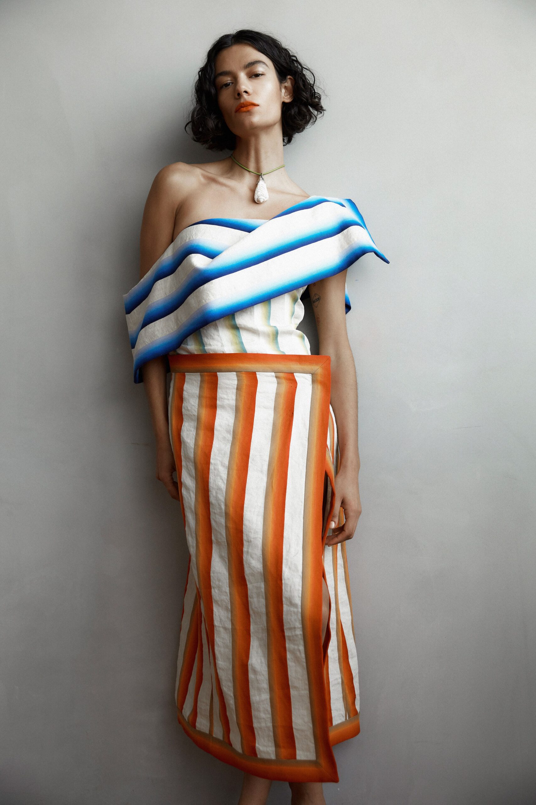 A fitted strapless dress in white with blue and orange stripes.
