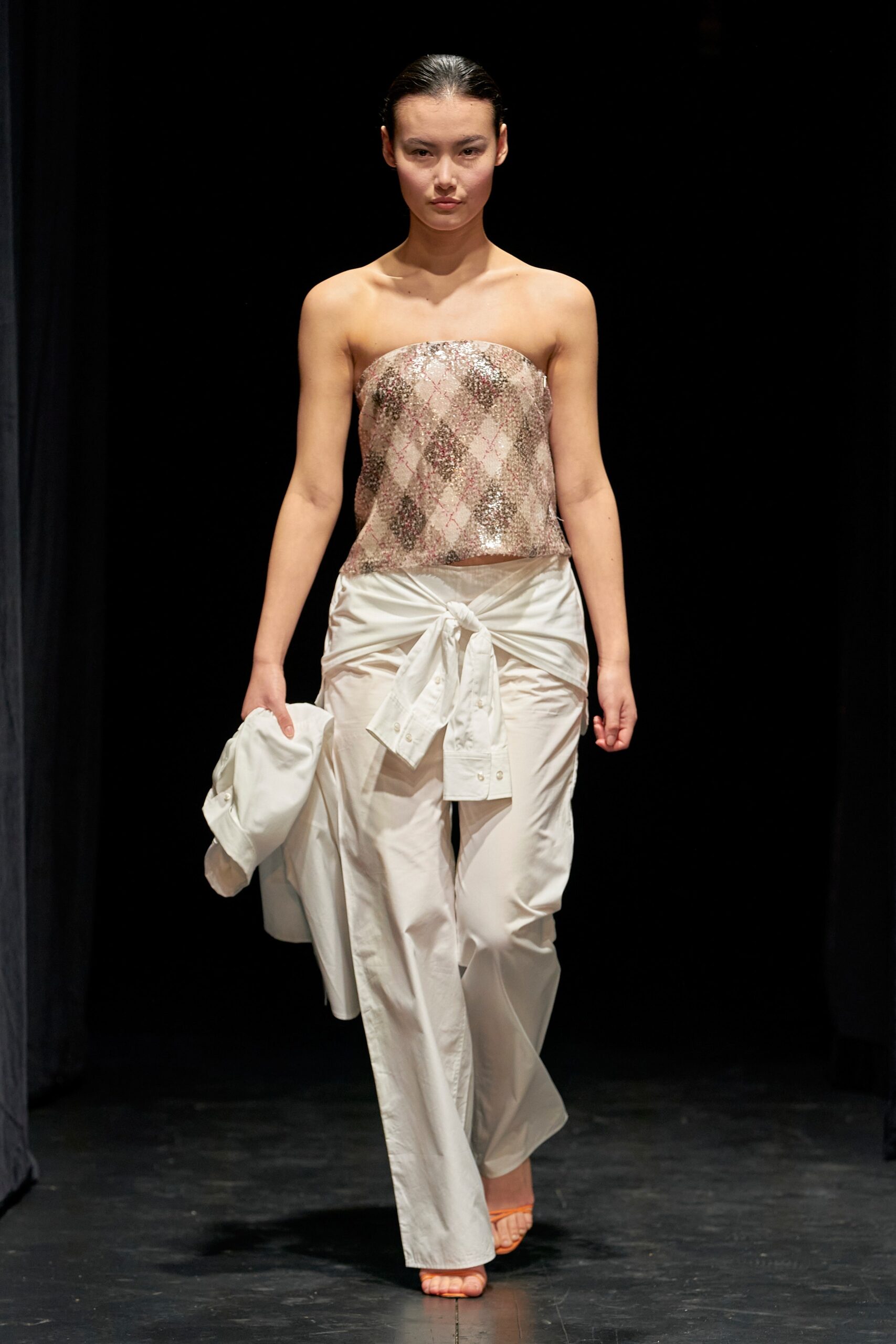 A relaxed white sleeveless top paired with high-waisted pleated pants for a chic look.