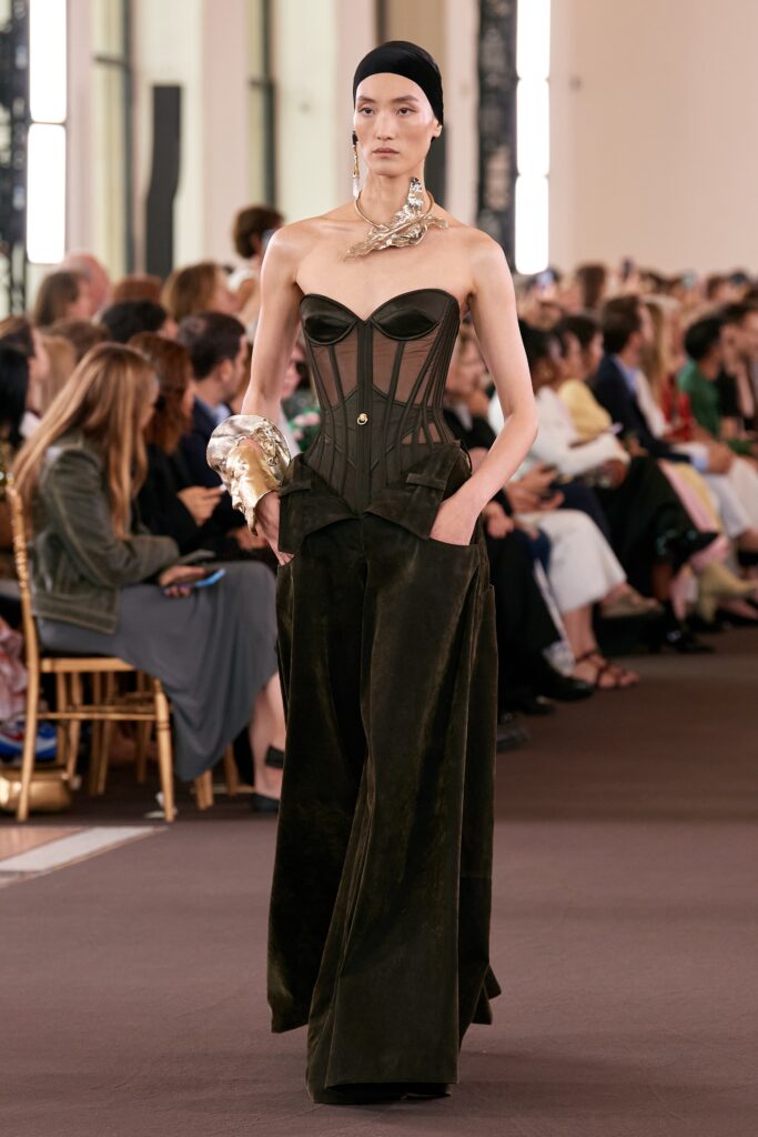 A fitted black silk corset with structured design paired with wide-leg pants.