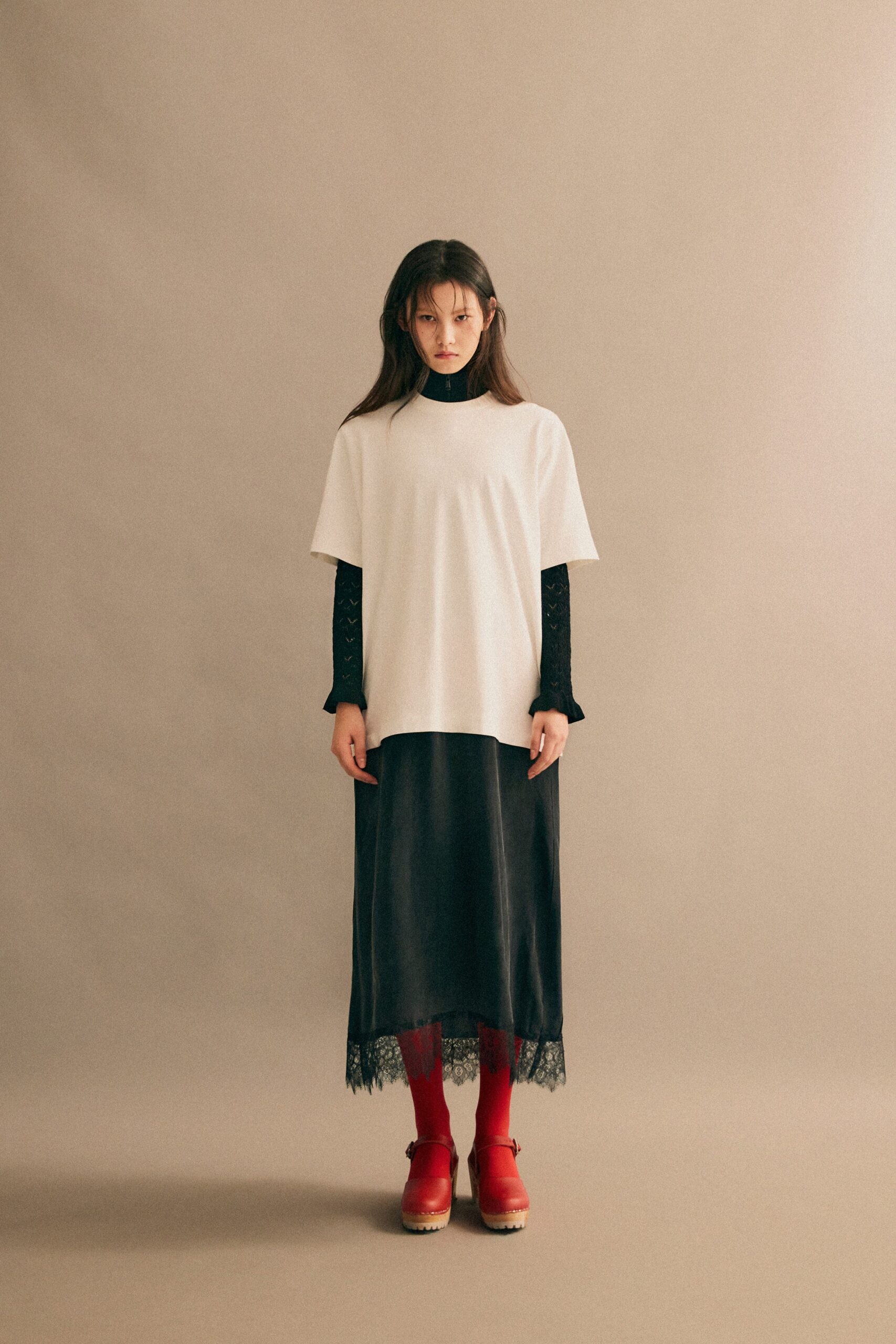 A relaxed black layered dress paired with a short-sleeve white top featuring embroidered details.
