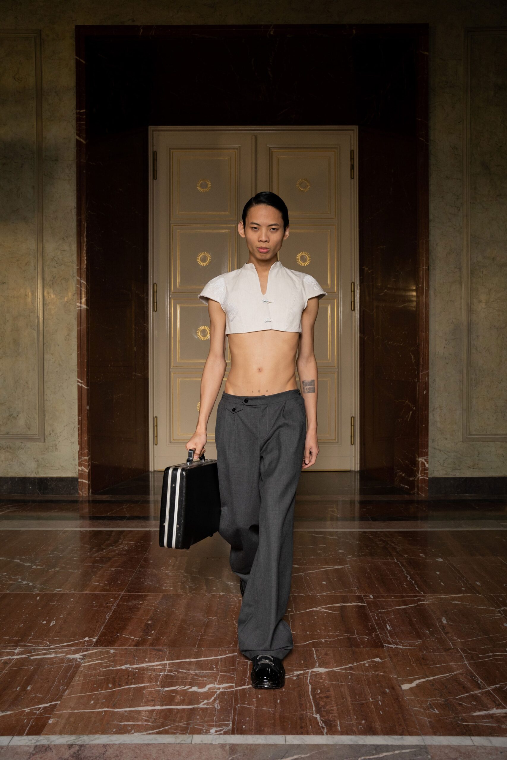 A fitted white cropped top with a collared design paired with gray straight-leg pants.