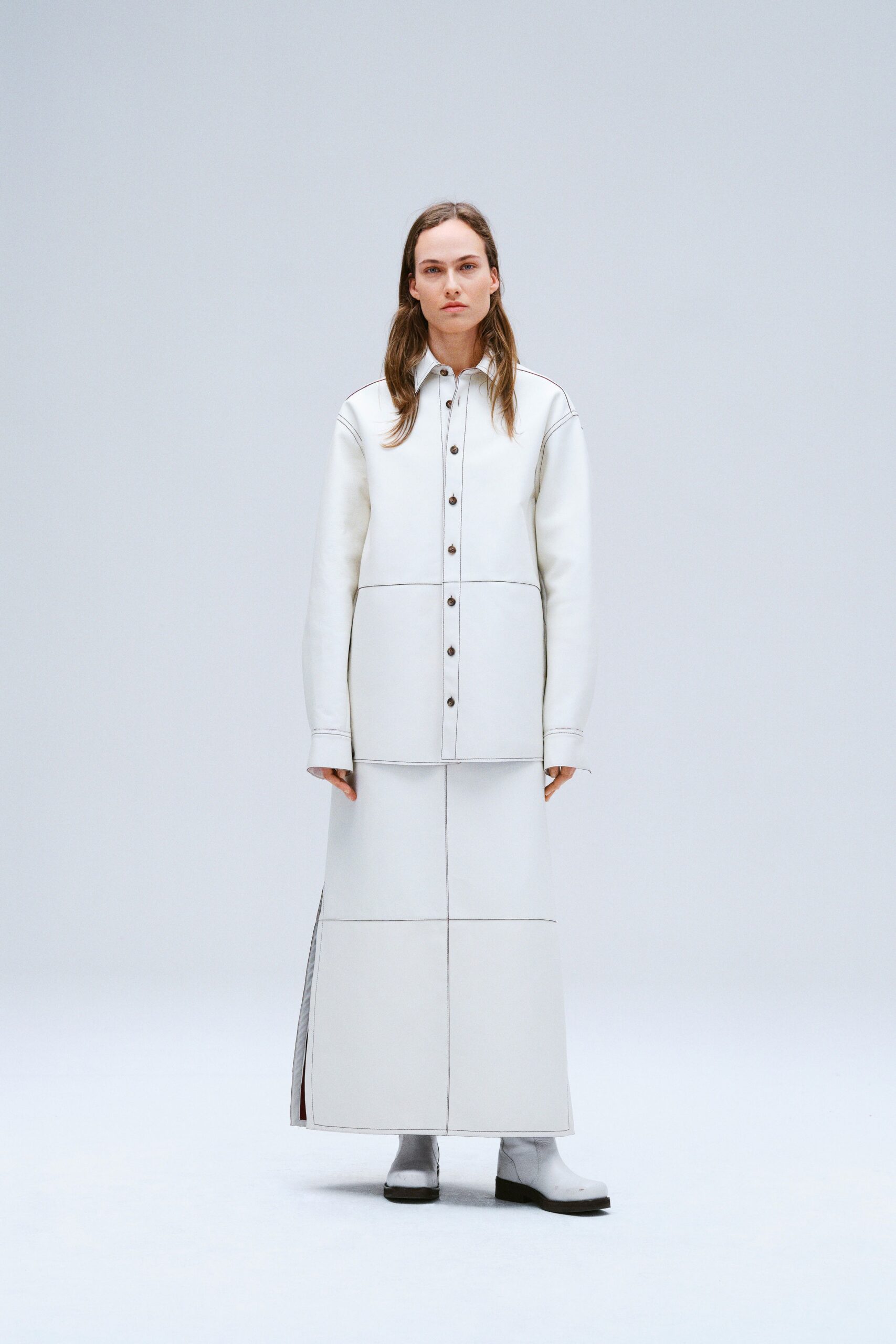 A fitted white leather dress jacket with long sleeves and an asymmetric design.