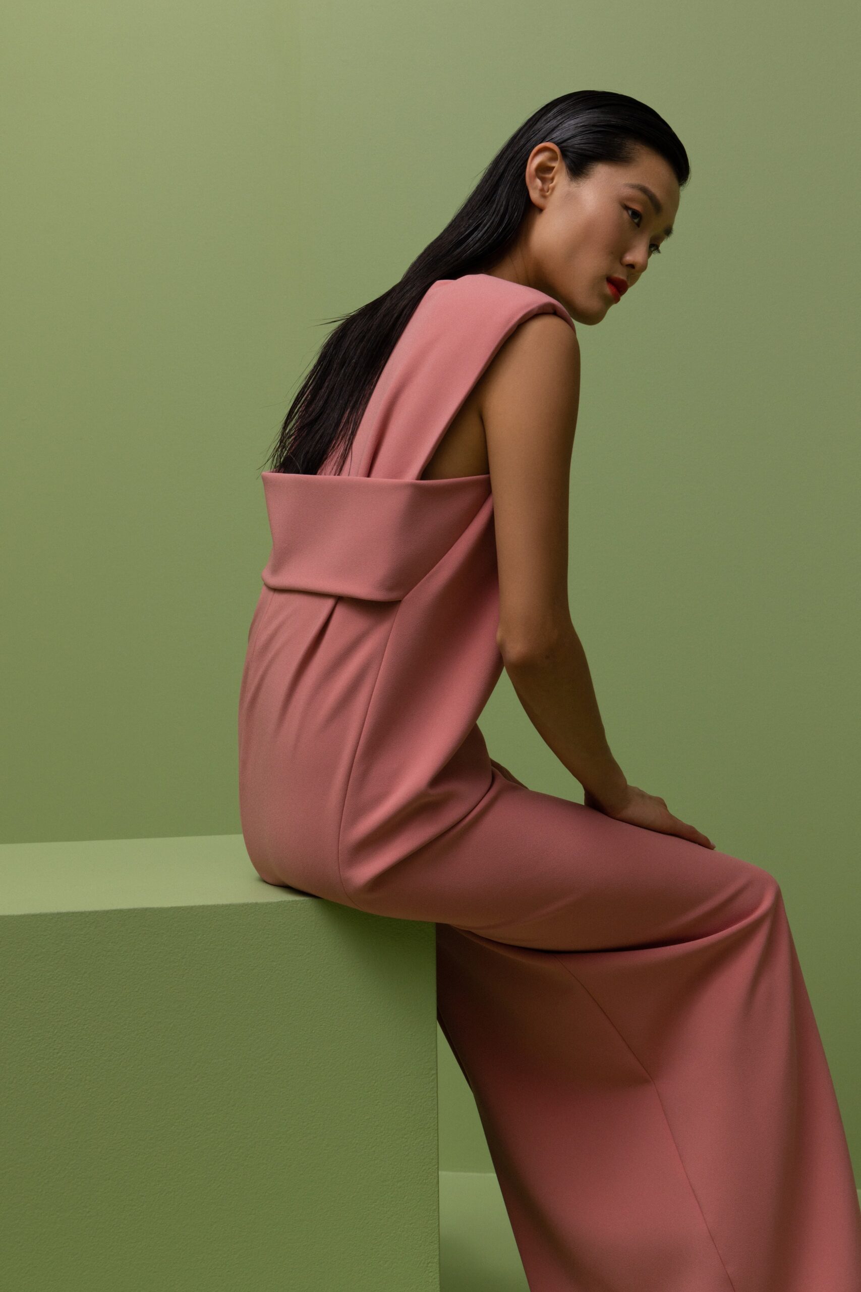 A fitted pink silk dress with a sleeveless design and draped detail.