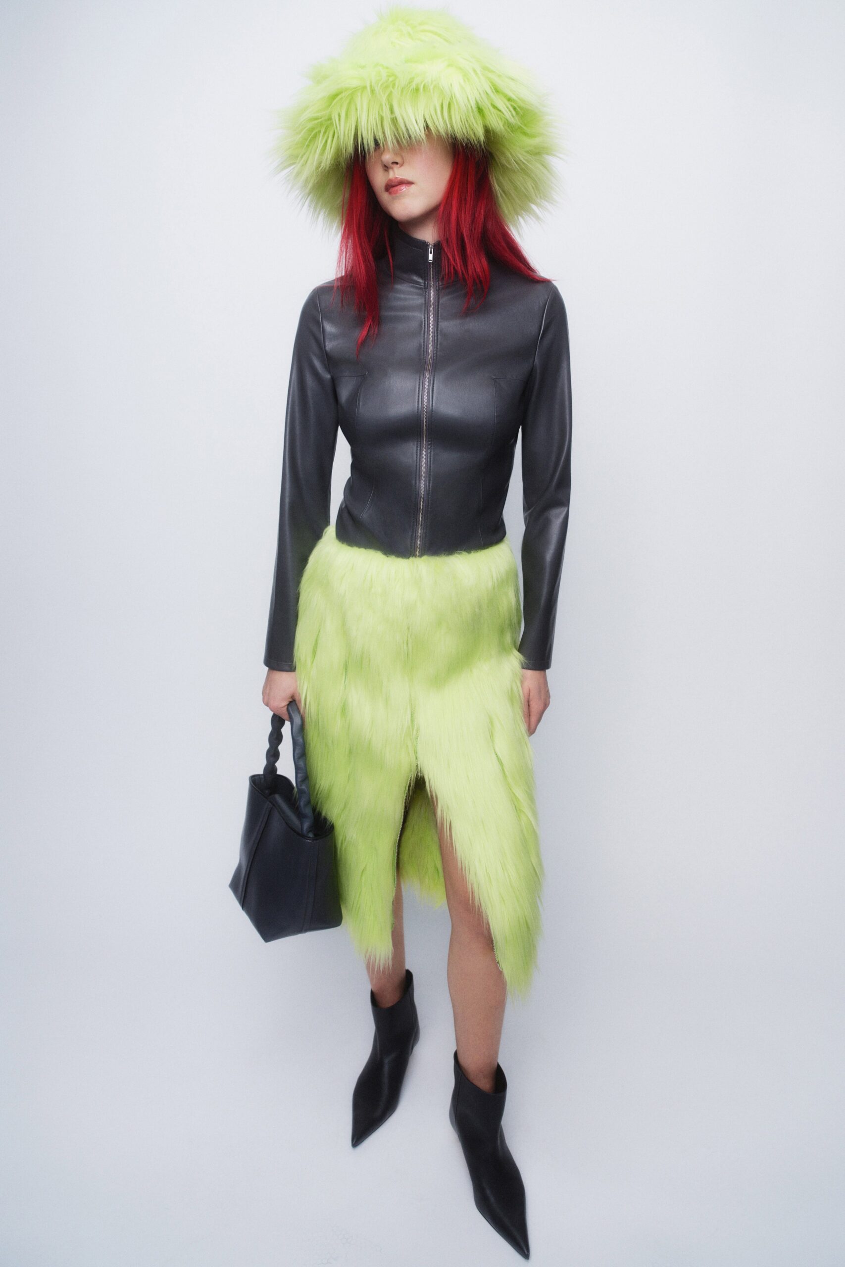 A fitted black leather dress with long sleeves, high neck, and an asymmetric slit design.