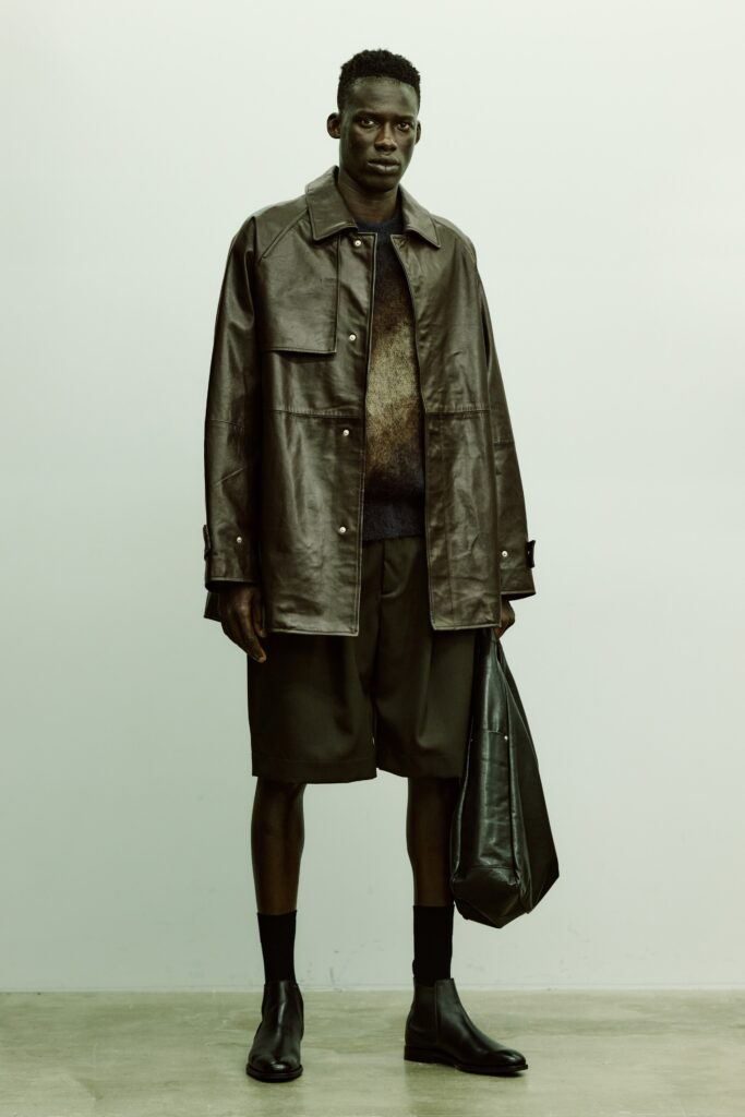 An oversized black leather jacket paired with fitted brown shorts for a modern look.