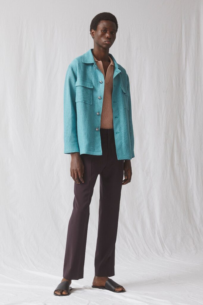 A tailored blue cotton jacket with a collared neckline paired with straight-leg black pants.