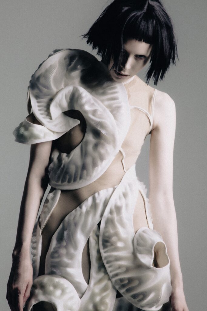A fitted white silk dress with a high neckline and asymmetric design details.