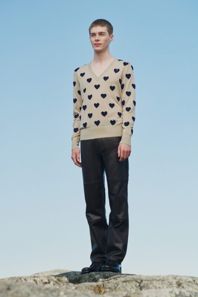 beige heart-printed sweater and black leather pants