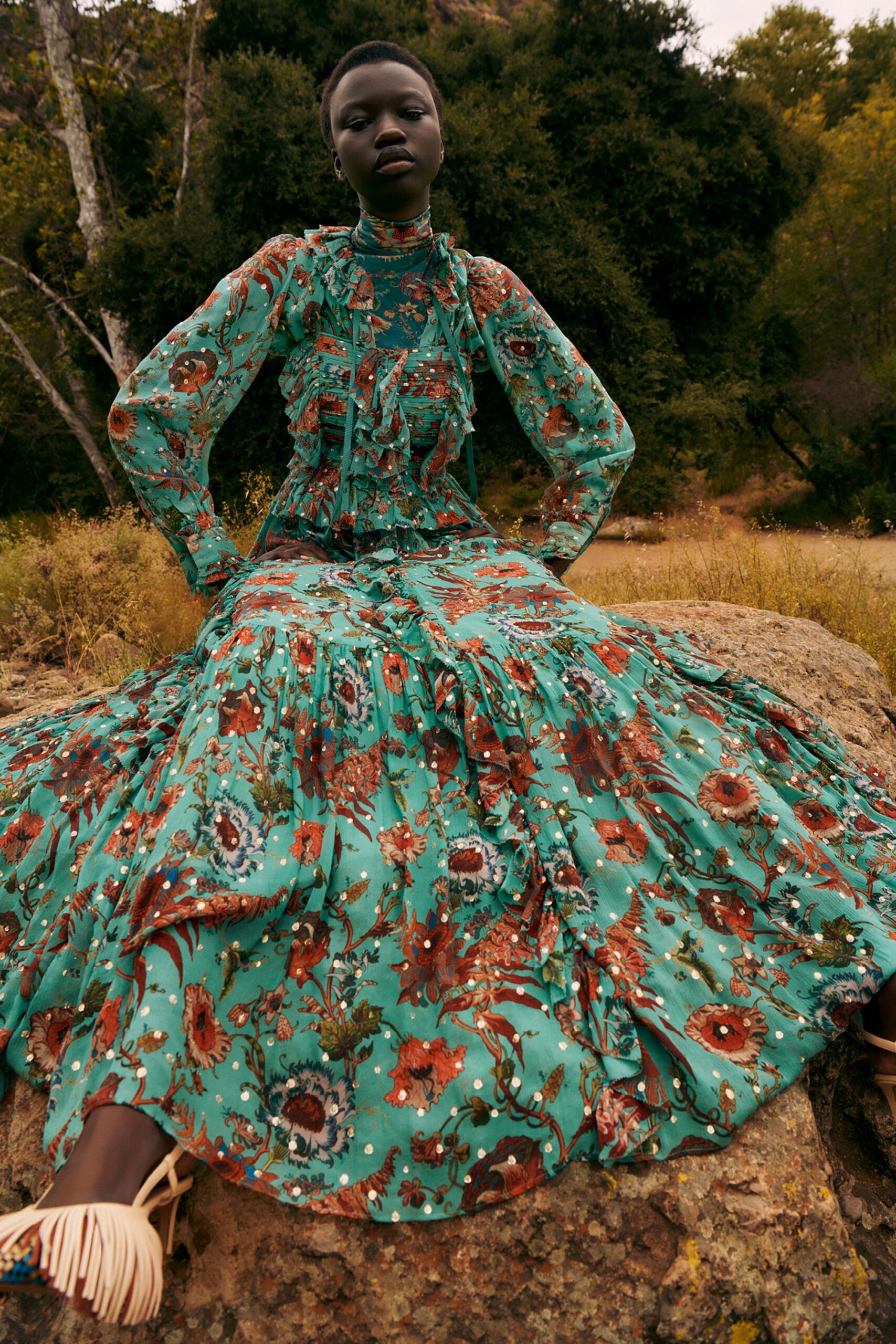 A relaxed green dress with long sleeves, a collared neckline, and a flared silhouette featuring floral patterns.