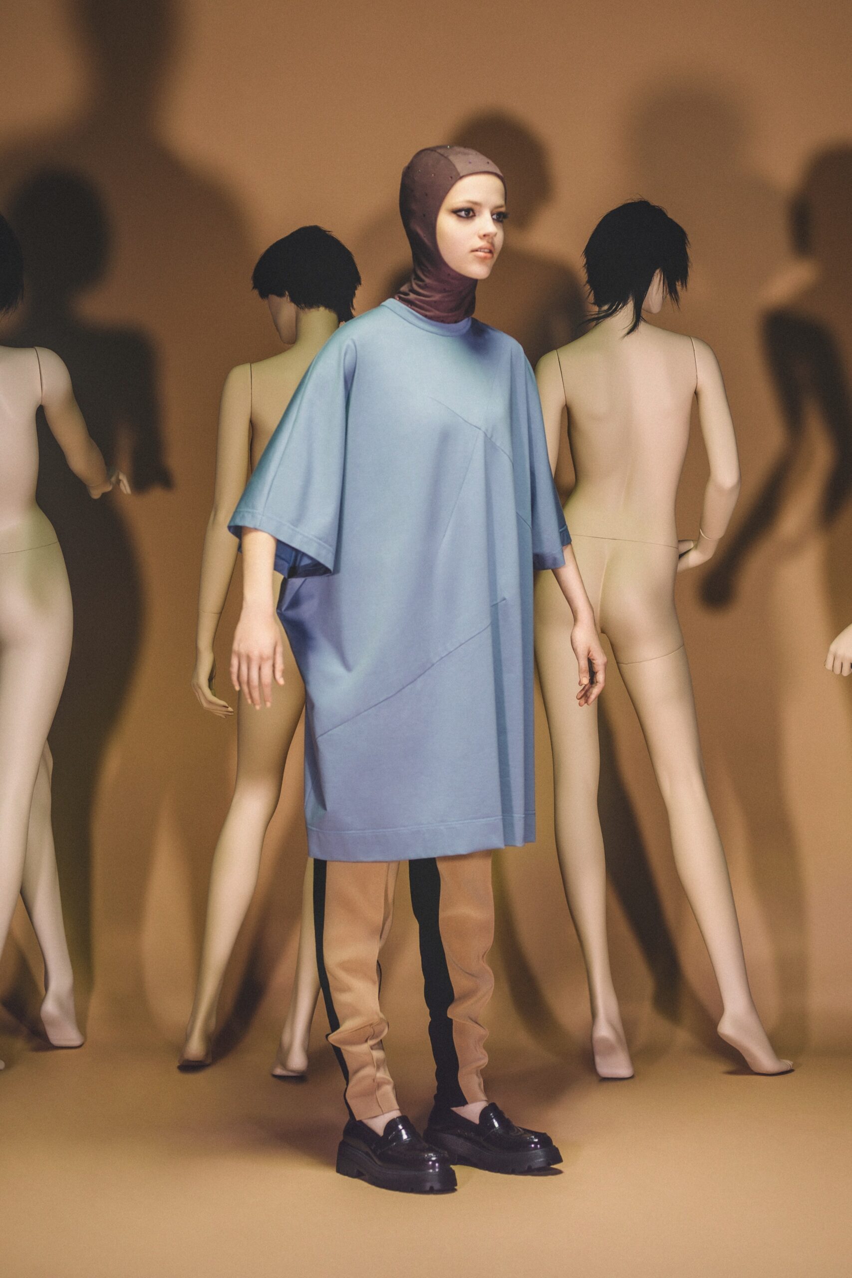 A relaxed blue dress with short sleeves and a high neck, paired with beige pants featuring an asymmetric design.