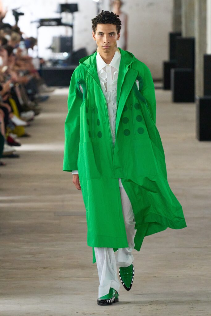 A relaxed green coat with long sleeves and an asymmetric design detail.