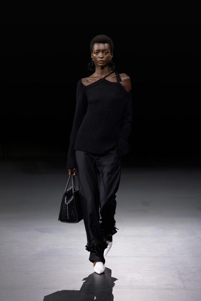 A fitted black long-sleeve knit sweater paired with sleek black silk pants.