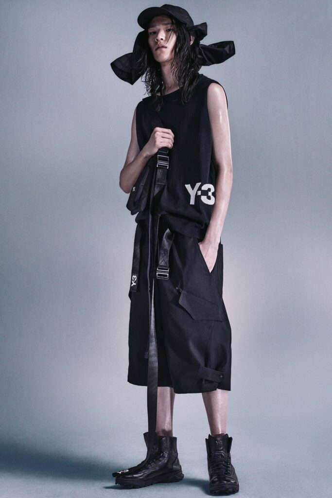 A relaxed black sleeveless top paired with black pants featuring an asymmetric design and zippered details.