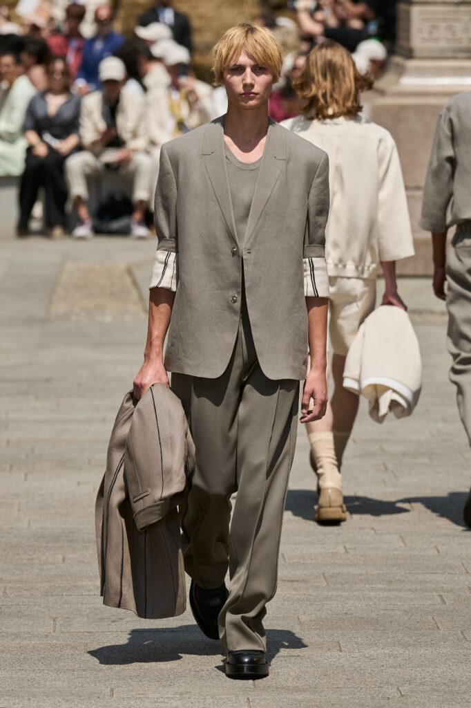A tailored beige suit with long sleeves and a collared design, featuring buttoned details.