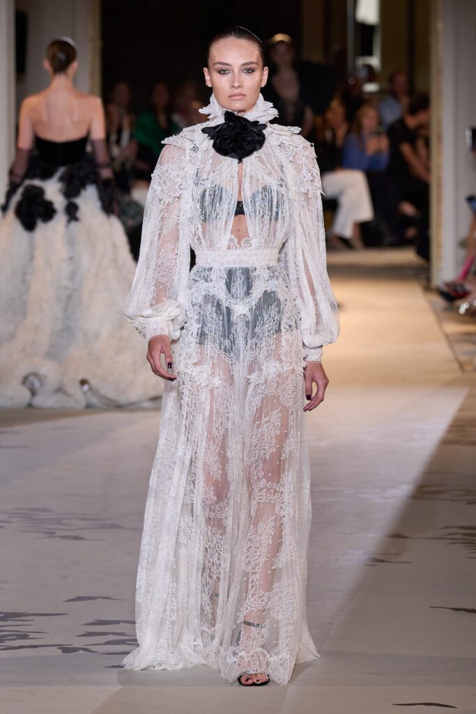 A fitted white lace long-sleeve dress with a V-neckline and sheer tiered design.
