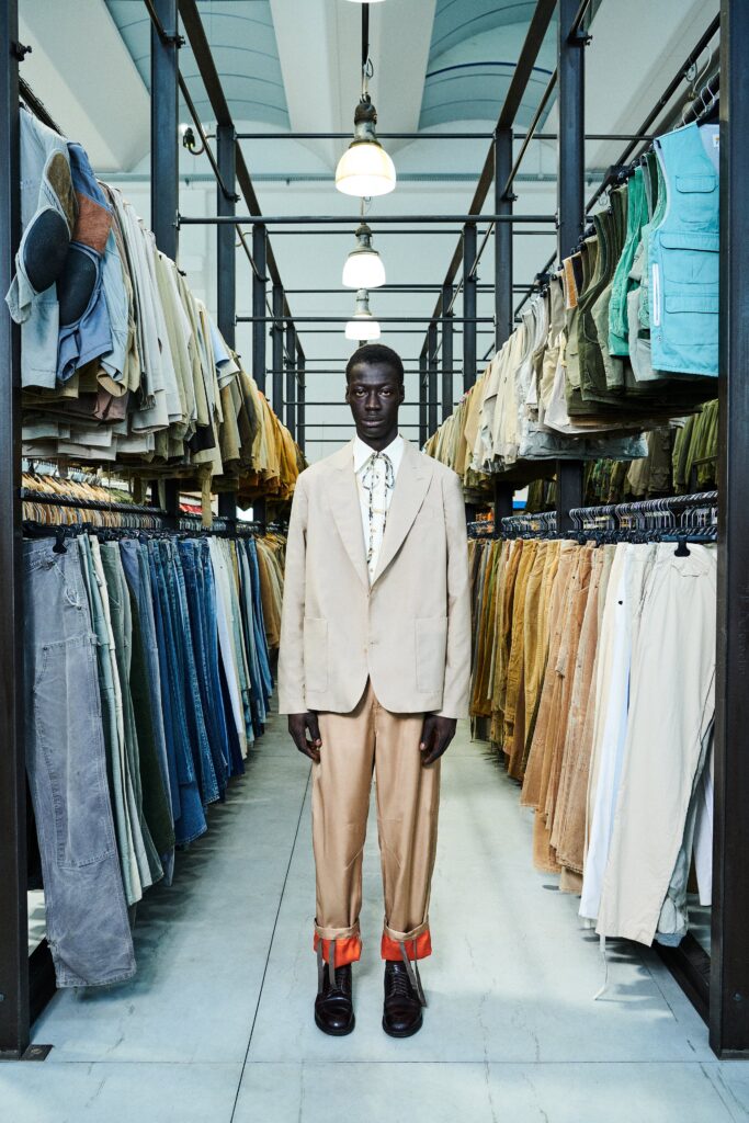 A tailored beige suit with long sleeves and a collared shirt, featuring buttoned details.