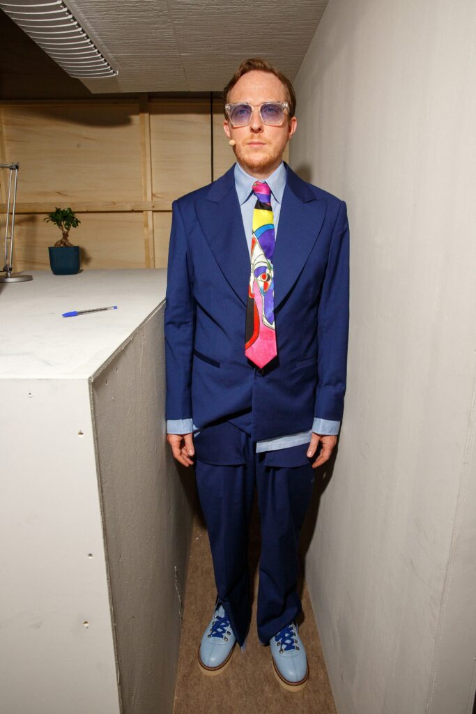 A tailored blue suit with long sleeves and a collared shirt, featuring a buttoned design.