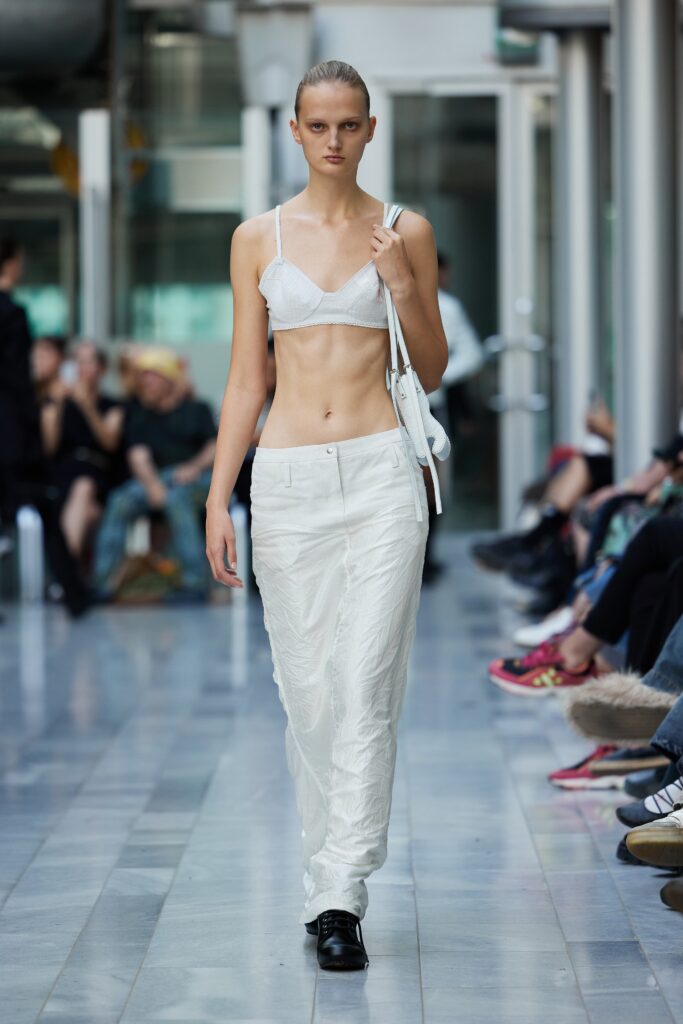A white sleeveless top paired with high-waisted pants, creating a chic and modern look.