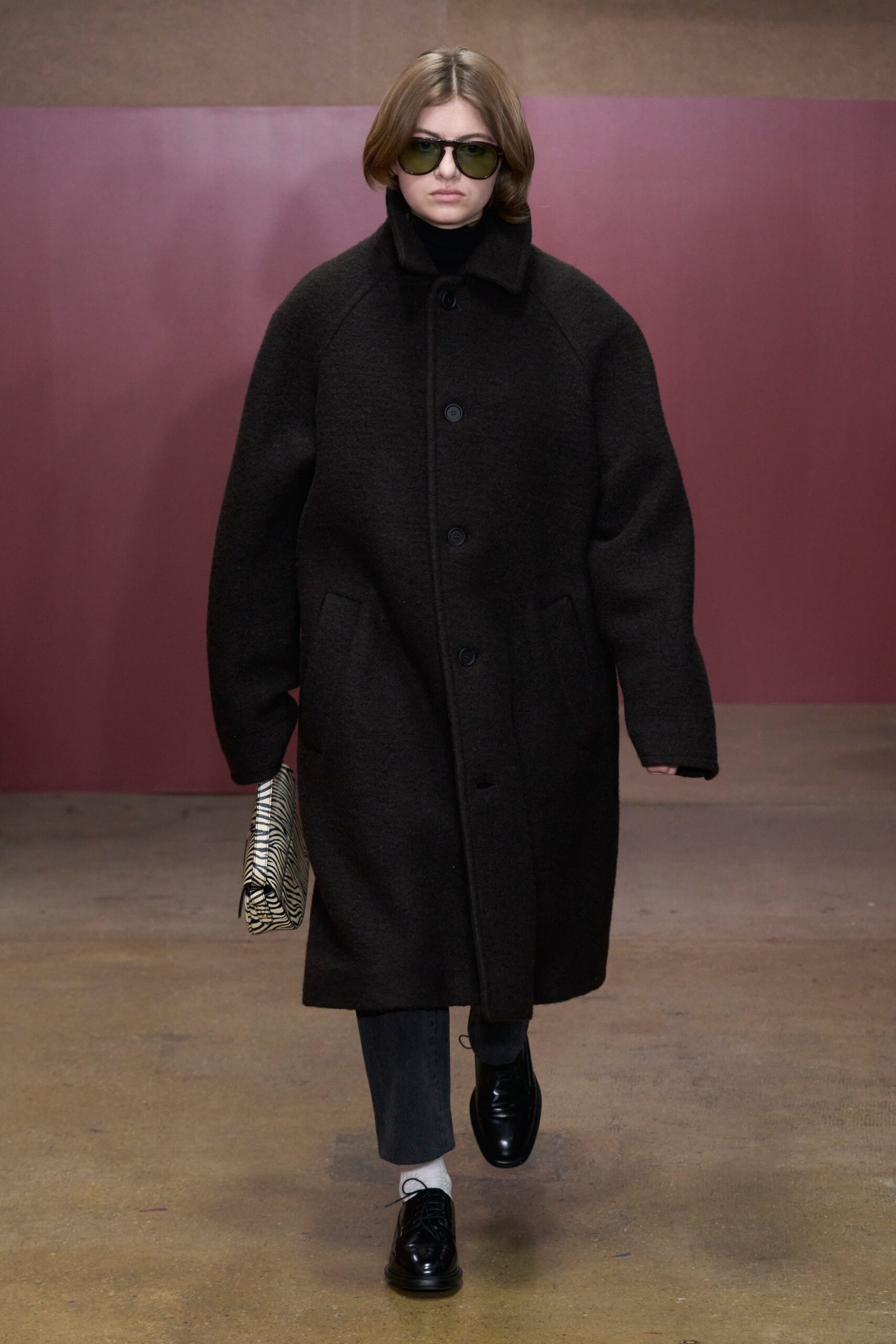 An oversized black wool coat with long sleeves and a collared design, featuring buttoned details.