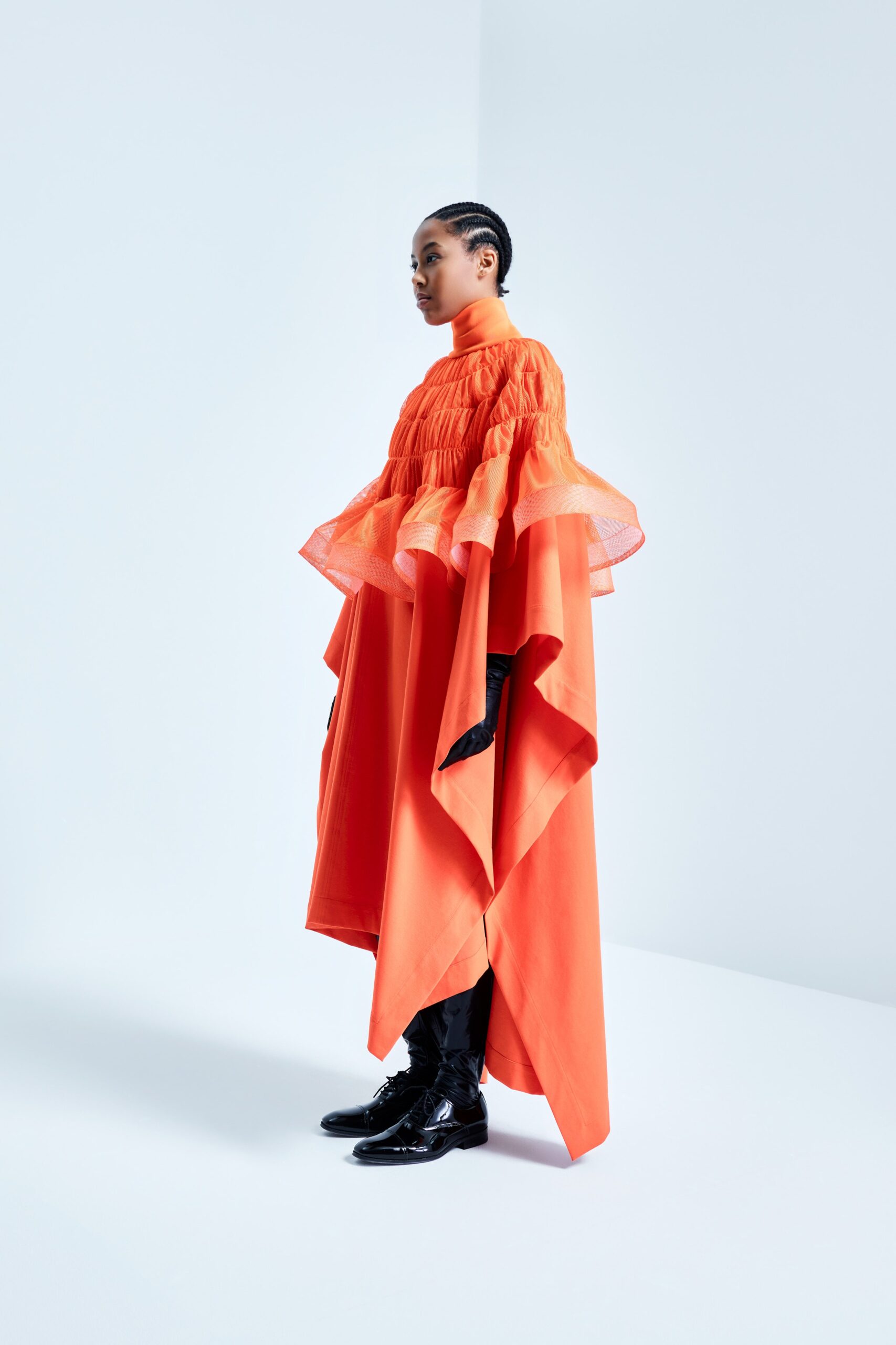 This dress features a high-neck design with voluminous long sleeves, creating a dramatic silhouette. The layered construction adds depth and movement, allowing the fabric to flow gracefully with each step.