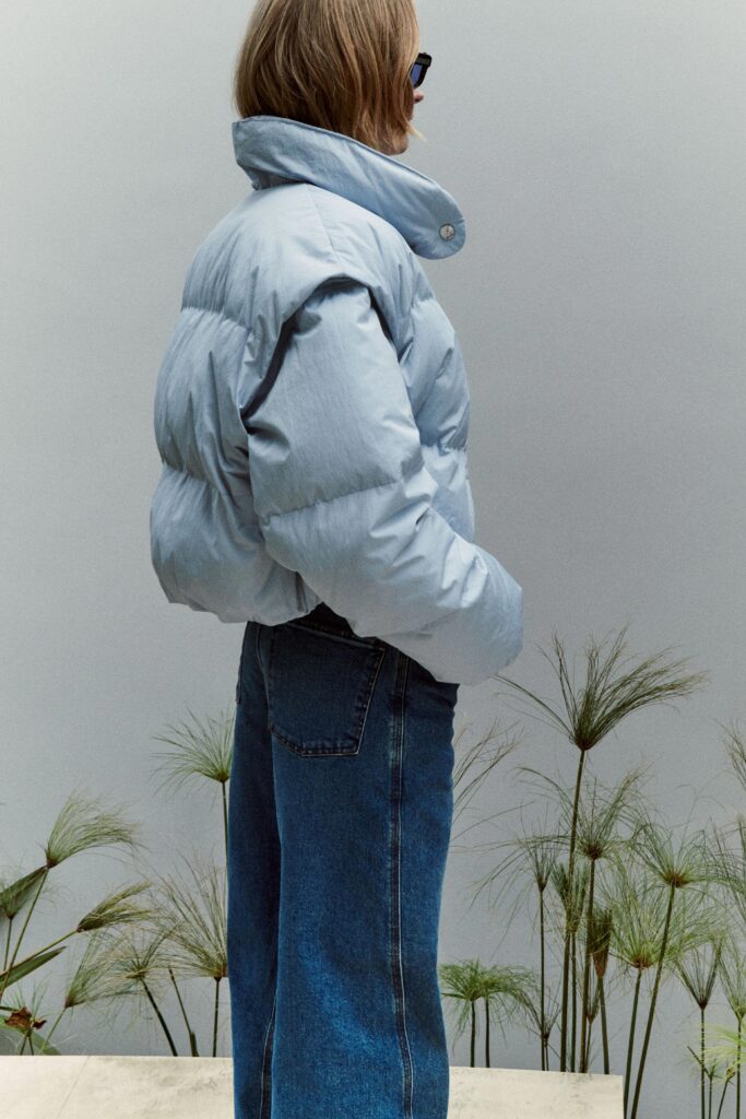 A relaxed blue cotton jacket with long sleeves and a collared design paired with denim pants.
